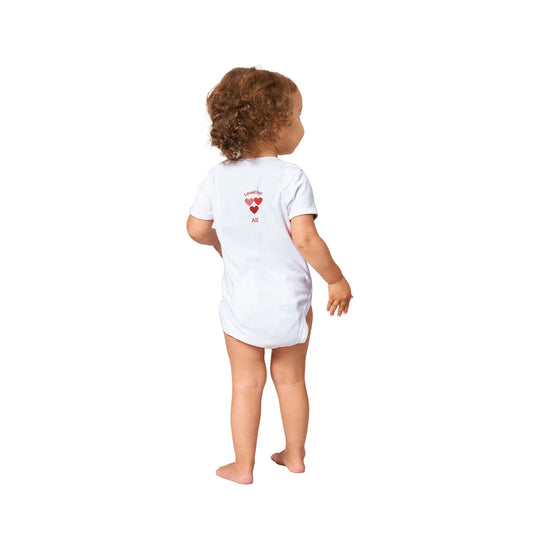 White baby bodysuit, three Pink hearts, Icelandic text 'Loved by All',on back customizable with baby's name on front.14ca6c9a-4364-46ad-81b3-91bbb8195523